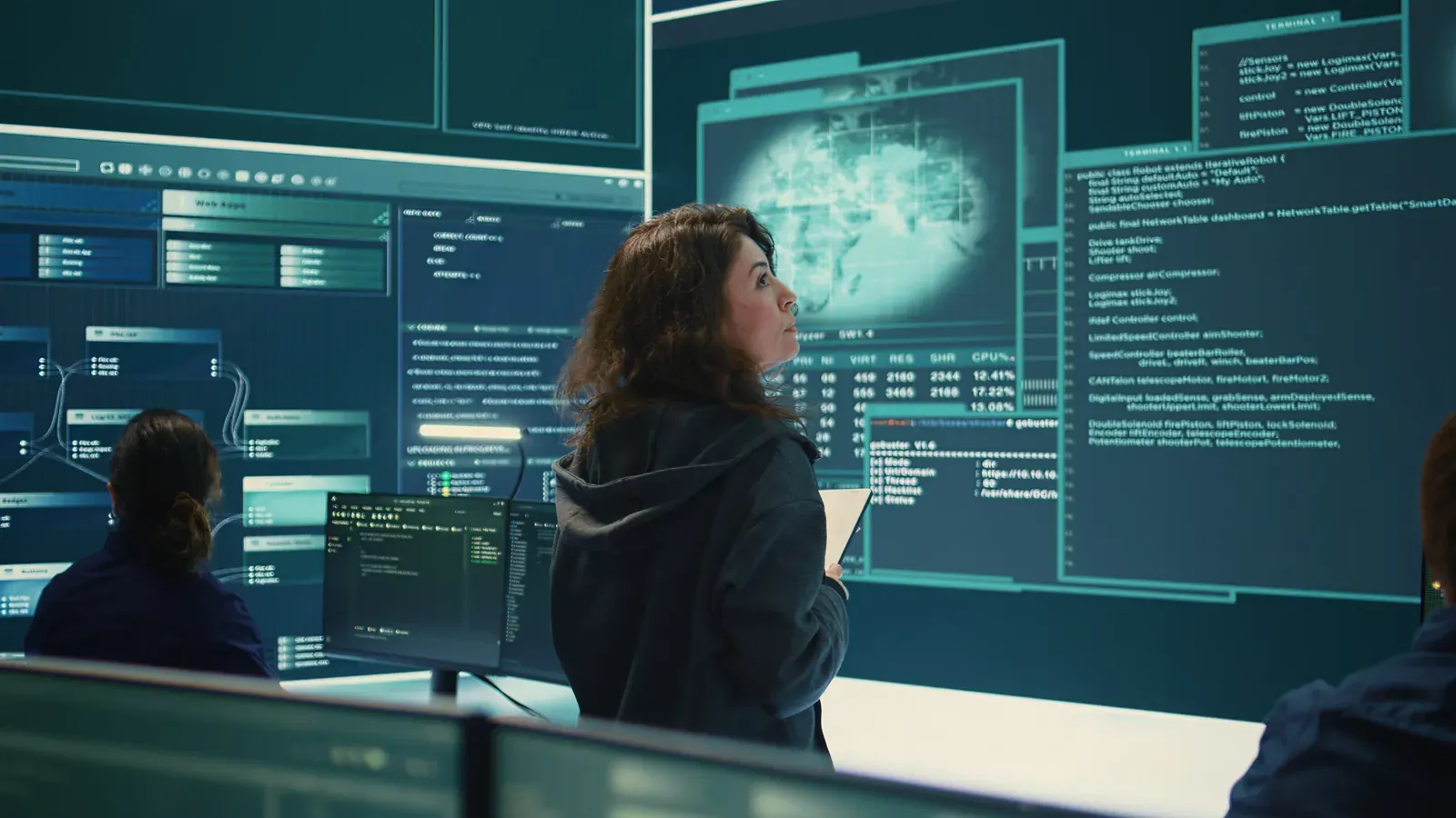 Investigators reviewing digital evidence across large screens in a darkened operations room