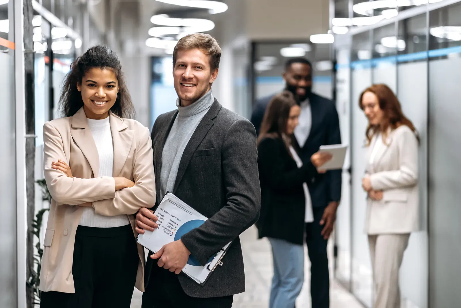 Consultants holding governance documentation while colleagues confer in a corporate office